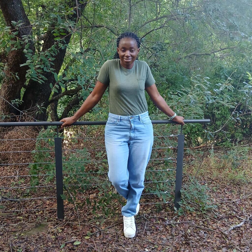 Young women smiling and posing in front of a fence in the forest